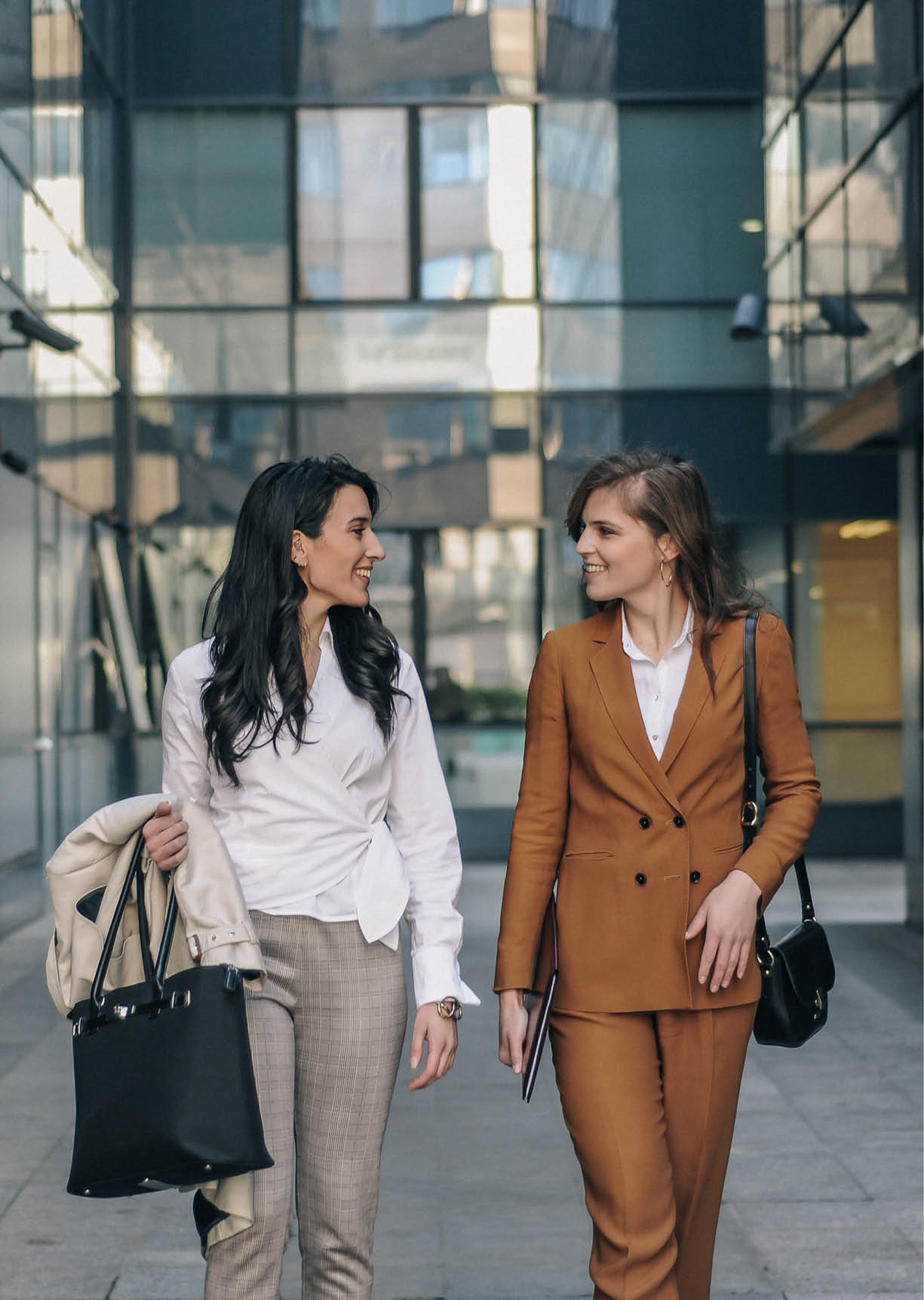 Two young businesswomen outdoor in front of the office building