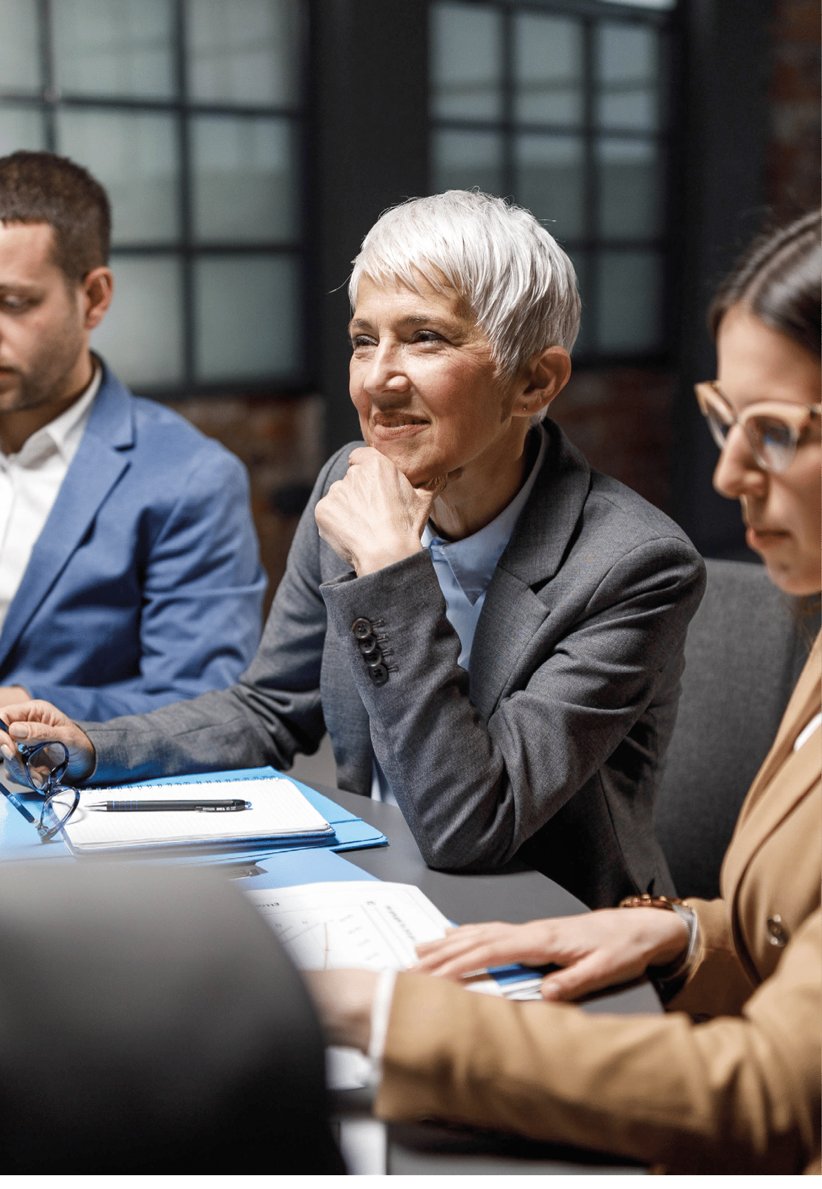 Happy senior entrepreneur listening to her colleagues during a meeting in the office.